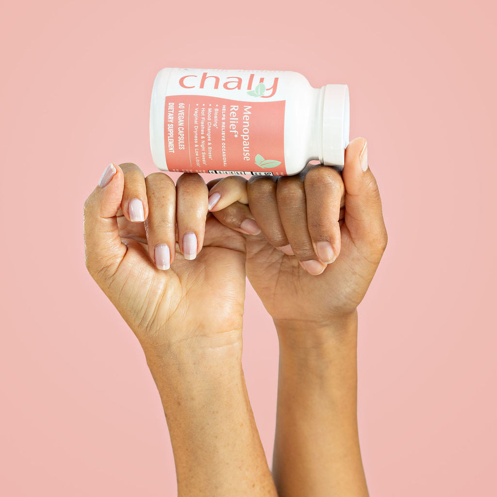 Two hands holding a bottle labeled 'chaly' against a pink background
